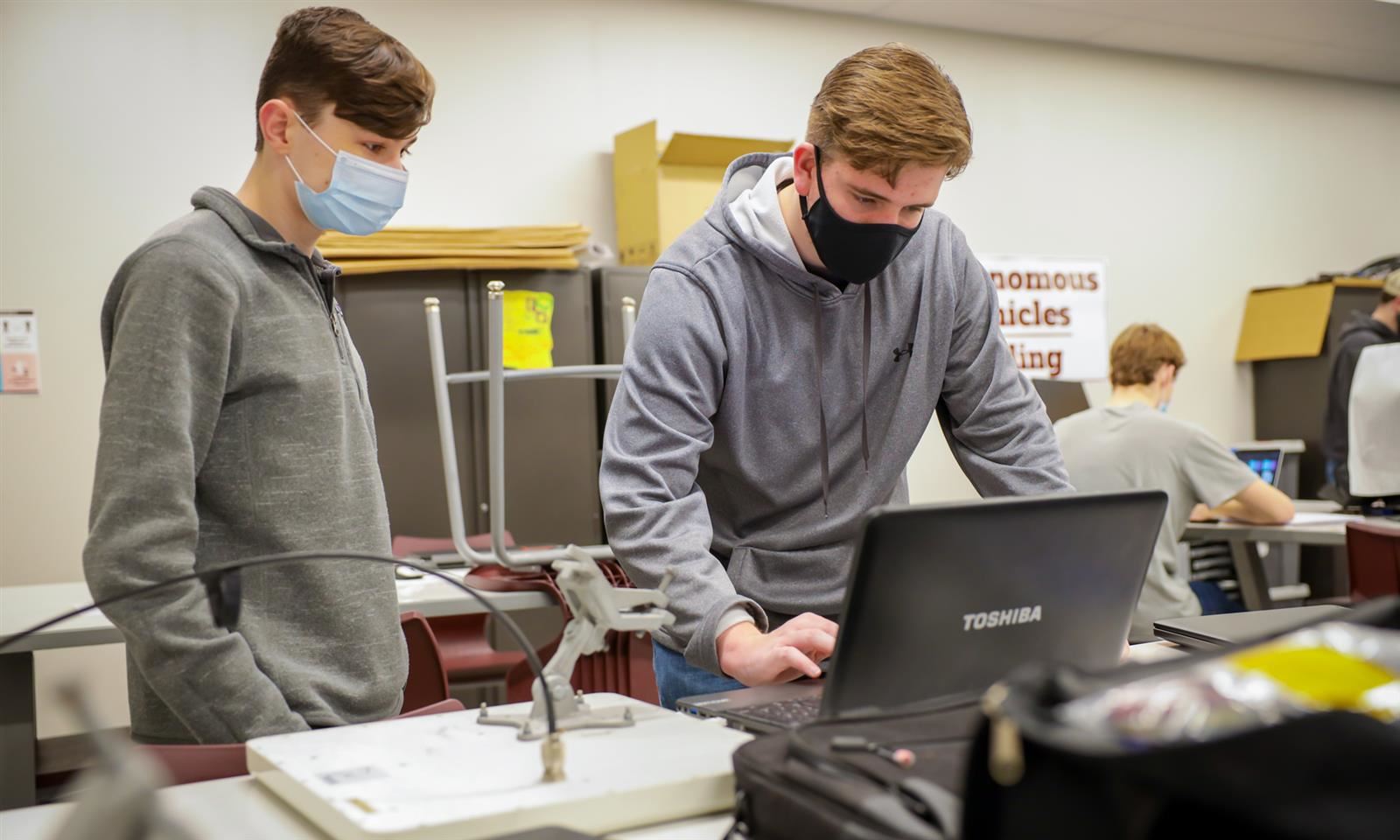 Two students work on a computer 